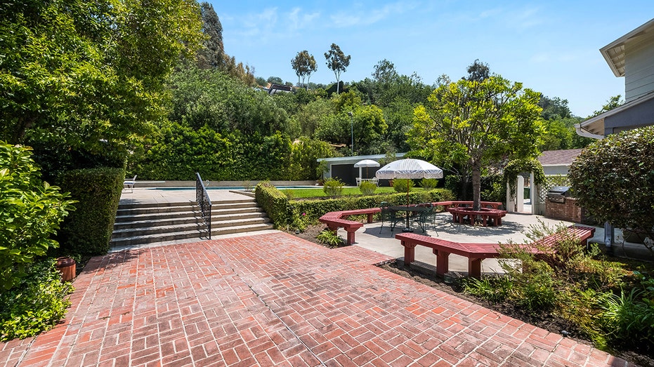 The backyard features a courtyard with red benches and a brick area.