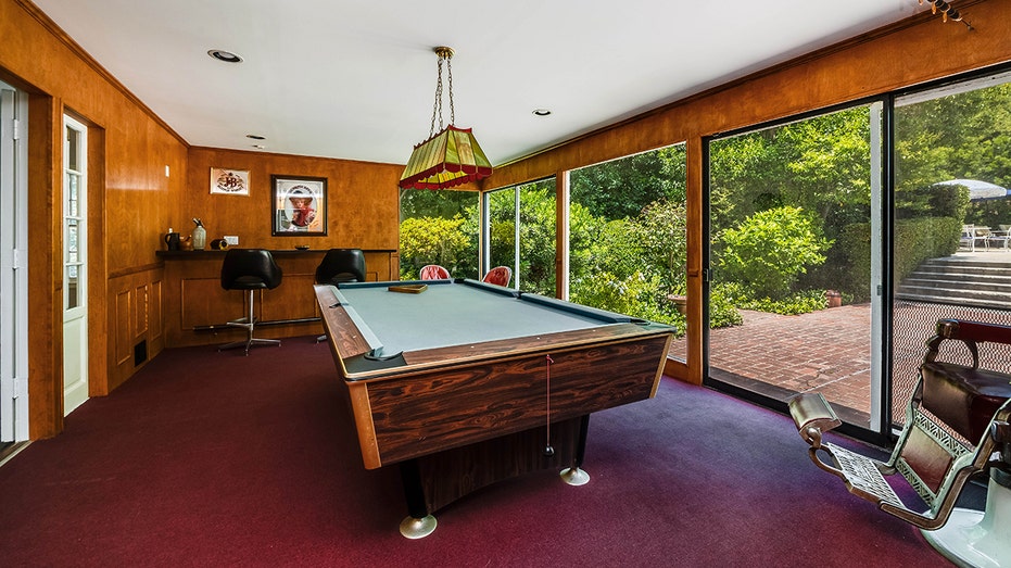 The home also includes a game room with a pool table and a bar, with floor-to-ceiling windows.