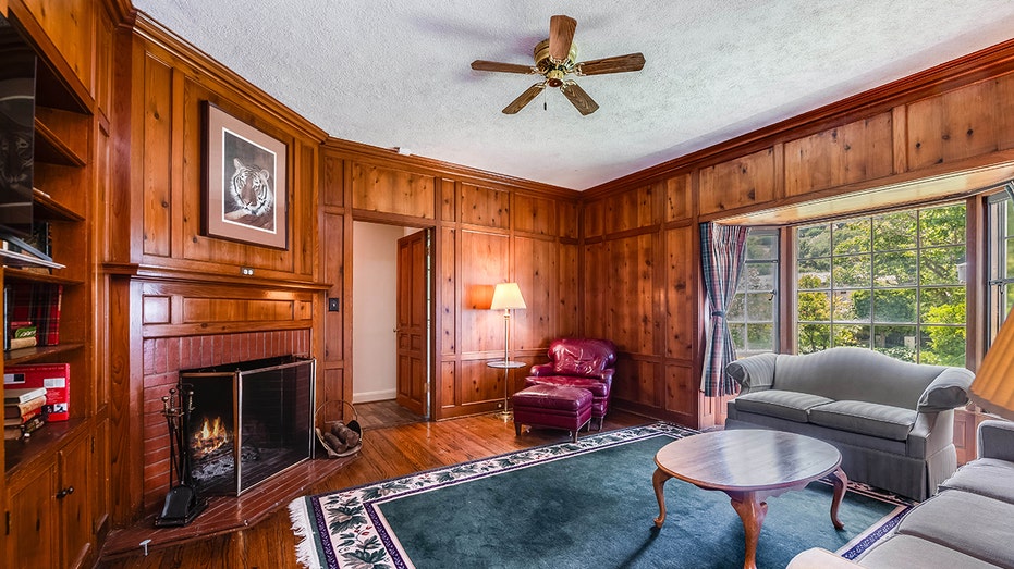 The library features wood-paneling on all the walls as well as a wood-burning fireplace.