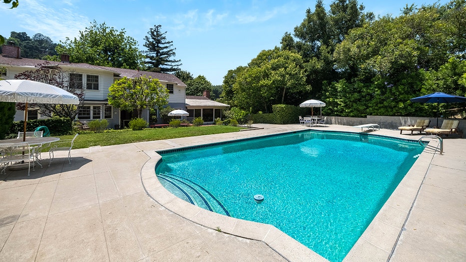 The backyard also features a sizable swimming pool and grass area.