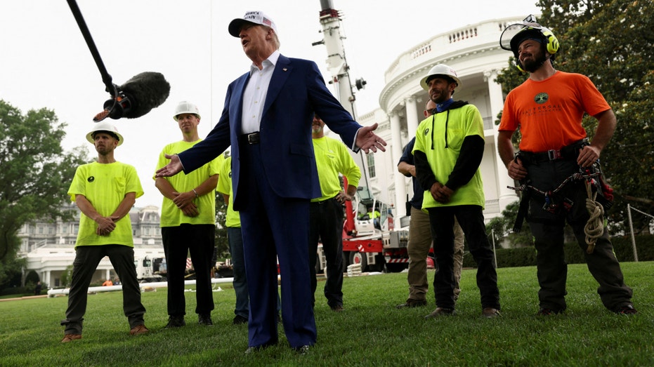President Donald Trump speaks to members of the media accompanied by workers during the installation of a new flagpole on the South Lawn at the White House in Washington, D.C., on June 18, 2025.