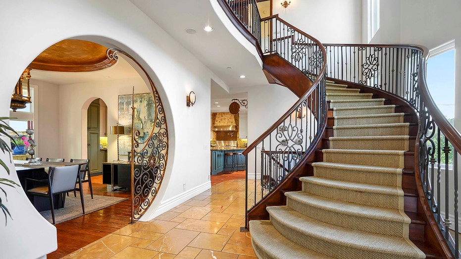 The double-level entryway features tiled floors and a grand staircase leading upstairs.