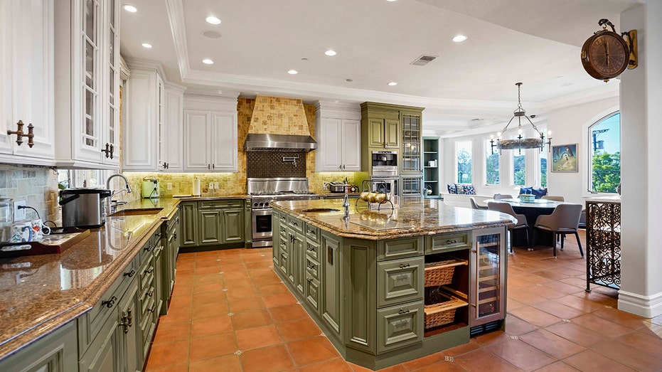 The kitchen features a large eat-in center island with green cabinets and a double oven.
