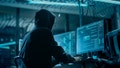 Shot from the Back to Hooded Hacker Breaking into Corporate Data Servers from His Underground Hideout. Place Has Dark Atmosphere, Multiple Displays, Cables Everywhere. - Fox News