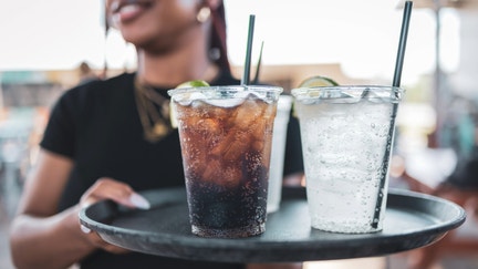 A server walks a tray of sodas to a table. - Fox Business News