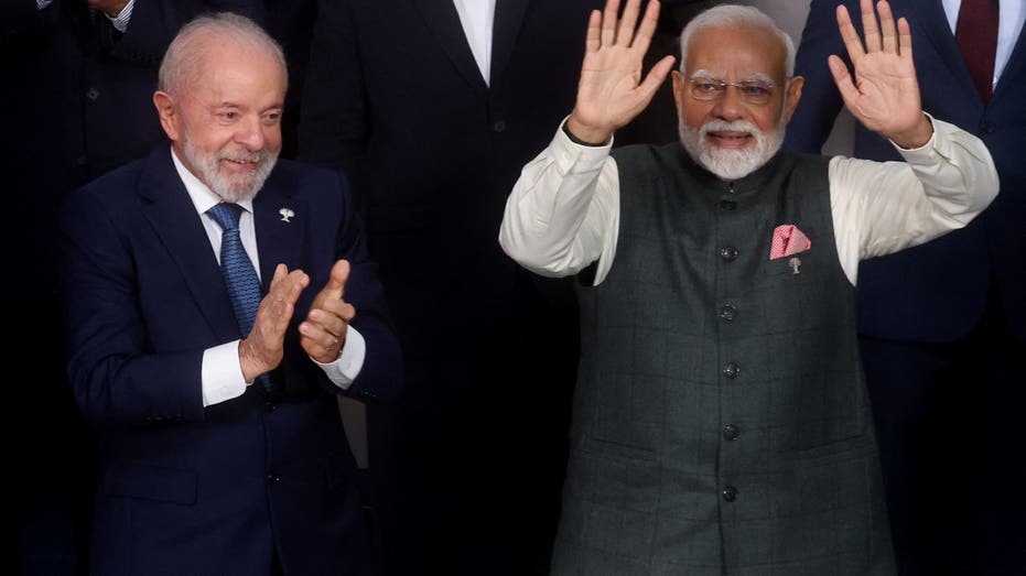 Brazilian President Luiz Inácio Lula da Silva applauds as Indian Prime Minister Narendra Modi waves to the crowd at a global summit.