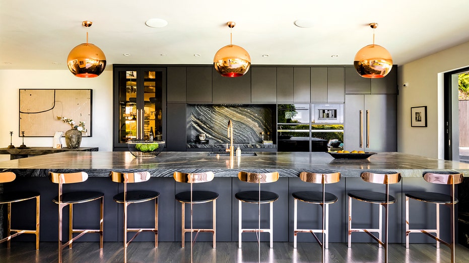 The sleek kitchen features a large eat-in island and black cabinets.