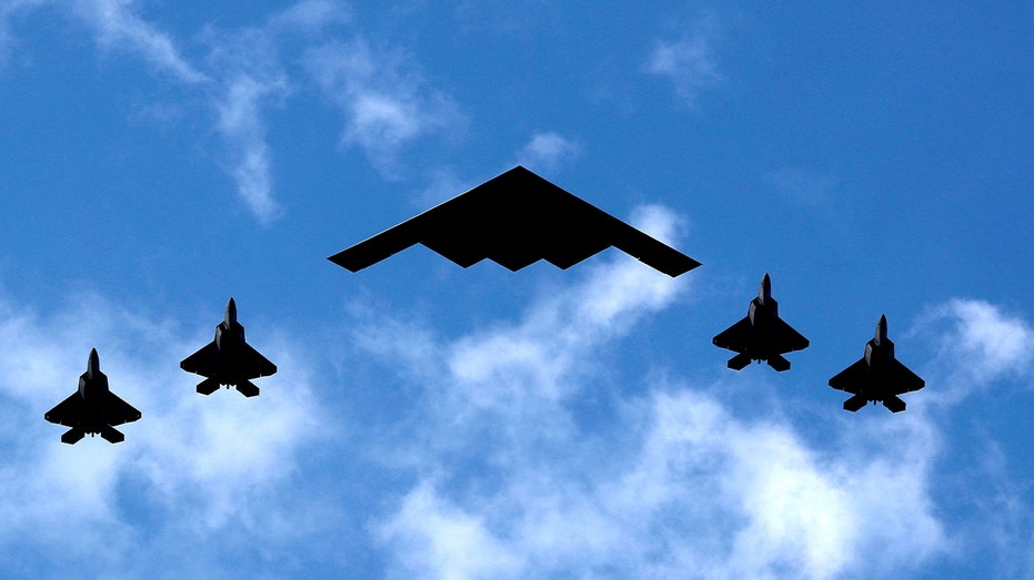 B-2 bomber flanked by F-22 Raptor fighter planes