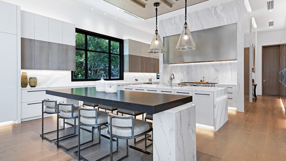 A kitchen with white cabinets and an eat-in center island.