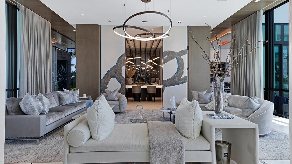 A living room with white furniture and unique light fixtures.