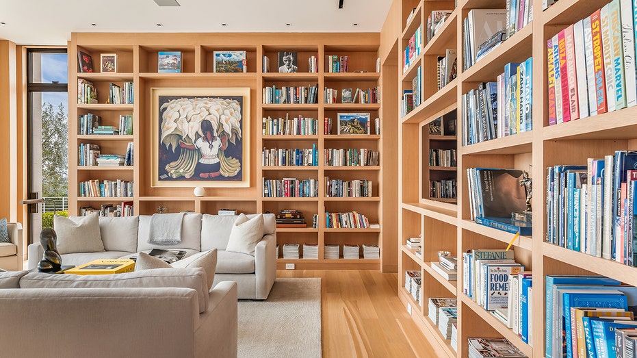 The library features floor-to-ceiling bookshelves and direct access to the backyard.
