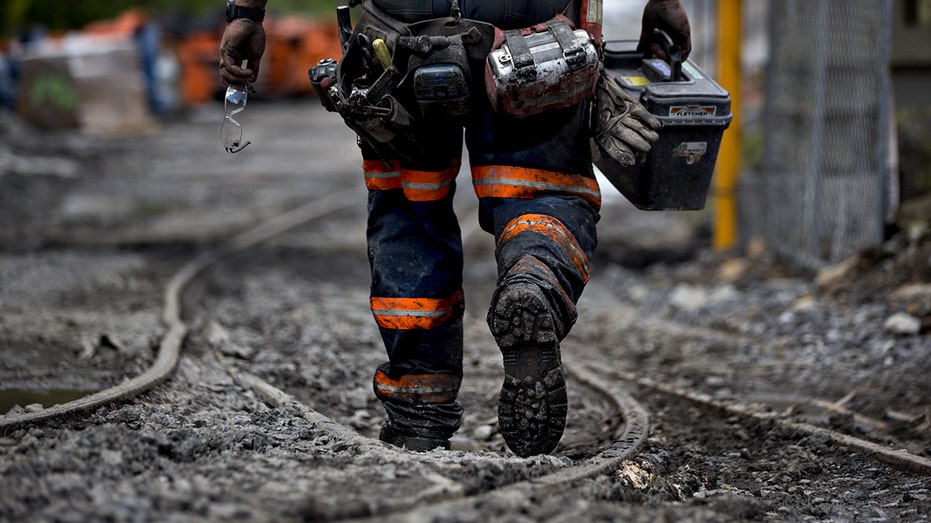 Miner walks next to mantrip shuttle tracks