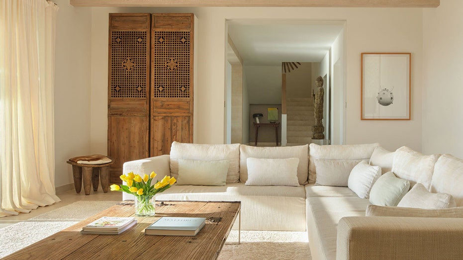 A living room with a white sectional sofa and a wooden wardrobe.