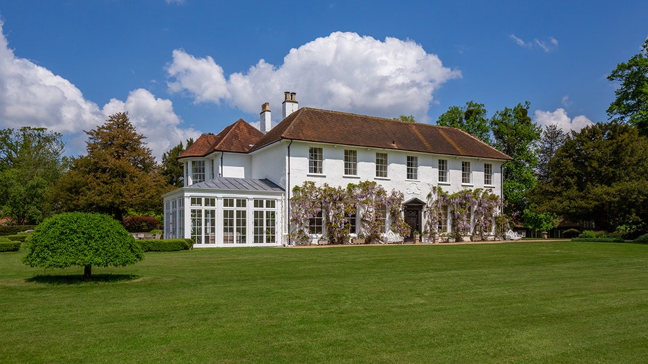 A two story house with a lot of windows and a grass area.