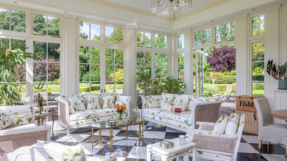 The sunroom is encased in windows and has black and white tiled floors.