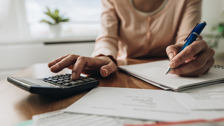 Close up of woman planning home budget and using calculator.