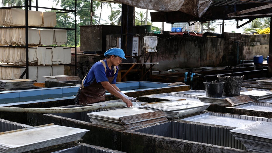 A worker in Thailand makes latex sheets