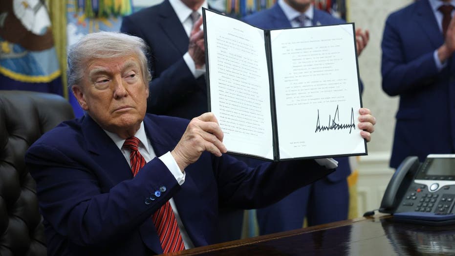 President Donald Trump holds up an executive order