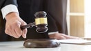 Close up of Male lawyer or judge hand's striking the gavel on sounding block, working with Law books, report the case on table in modern office, Law and justice concept. - Fox Business News