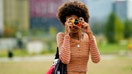 MILAN, ITALY - SEPTEMBER 25: A guest wears silver chain necklaces, a black / red / yellow / orange / blue striped long sleeves cropped t-shirt, a black shiny leather shoulder bag, a red hoodie sweater, a black shiny leather nailed / studded belt, white ripped shorts, silver rings, outside the MSGM fashion show during the Milan Fashion Week - Spring / Summer 2022 on September 25, 2021 in Milan, Italy. (Photo by Edward Berthelot/Getty Images) - Fox Business News