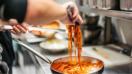 Young male chef making Bolognese pasta in a commercial kitchen. Close-up. - Fox Business News