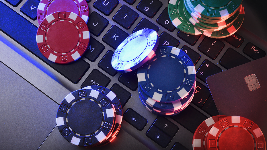Online game betting concept with chips on laptop keyboard and bank card. Top view.