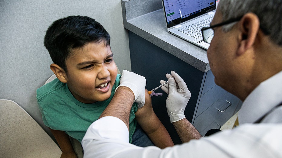 The boy receives a coffeed shot from the pediatrician
