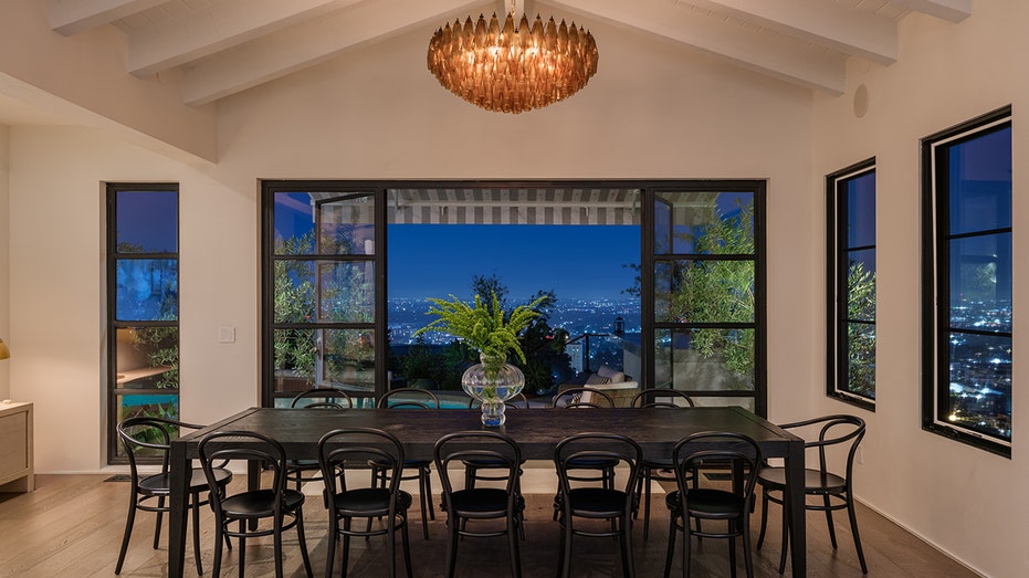 The dining table is in front of doors leading to the yard, providing views of the city below.