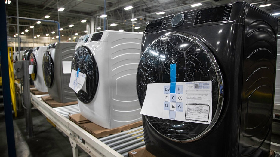 GE Appliances washer and dryers sitting on shelf of a factory.