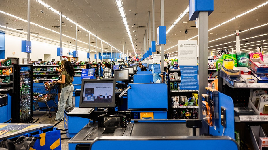 Automatic checkouts with cashiers and customers in the aisles of a Walmart.