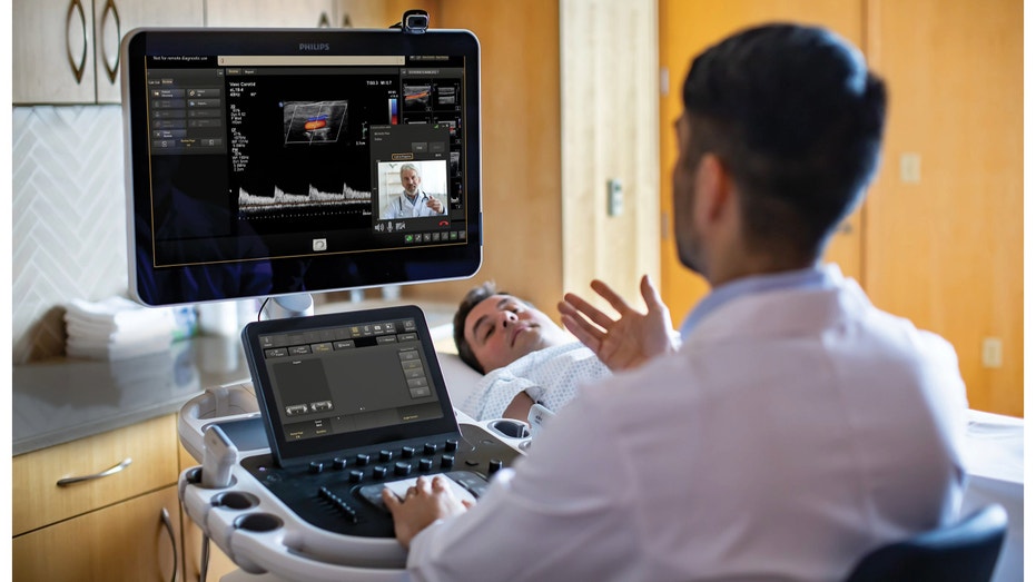 Two clinicians using Collaboration Live while patient is on the table undergoing an ultrasound scan.