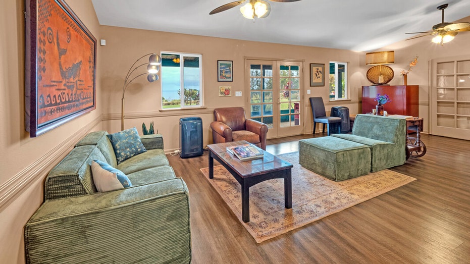 The sitting room features green sofas and a piano in the corner.