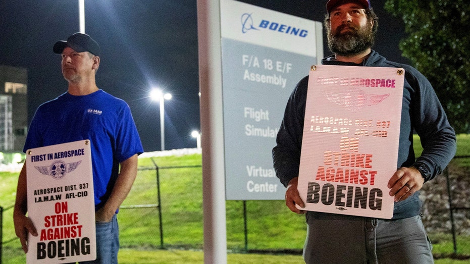 Workers display picket signs, as they protest during a walkout by members of the International Association of Machinists and Aerospace Workers (IAM) over contract negotiations, outside Boeing company's facility, in Berkeley, Missouri, U.S., August 4, 2025