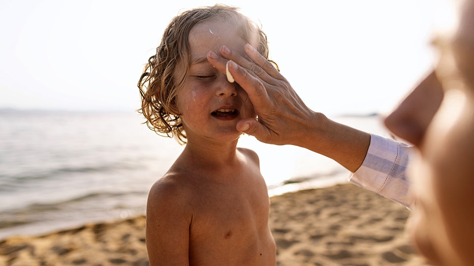 My mother, who applies sunscreen to her son's face.