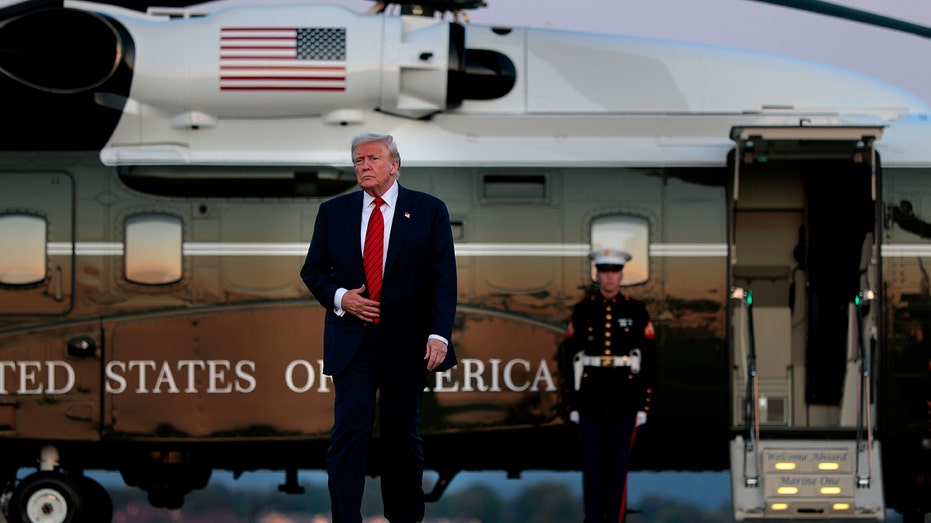 Trump walks away from Marine One helicopter with Marine standing guard in background