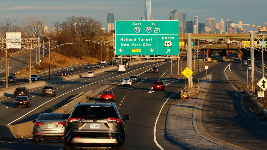 Vehicles travel on the New Jersey Turnpike in front of the skyline of New York City