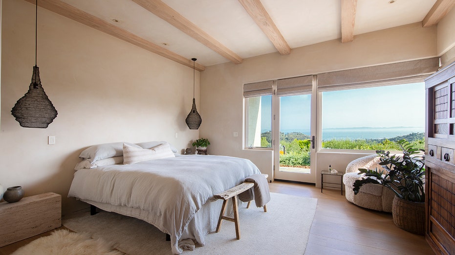 The primary bedroom features exposed wooden beams on the ceiling and access to the yard.