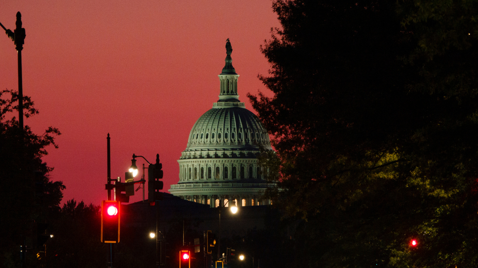The dome of the capitol building DC is seen against a red sky at sunset