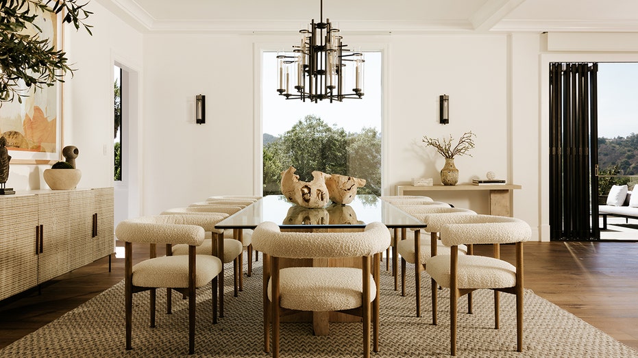 The dining room features a unique light fixture and a large window looking out onto the hillside.