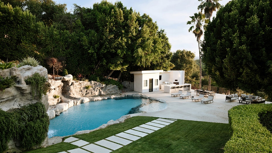 The grotto swimming pool features waterfalls, and an outdoor kitchen and lounge area can be found nearby.