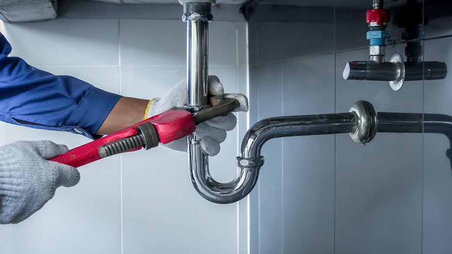 Plumber hands holding wrench doing repairing work at the sink and clogged pipe in bathroom carefully