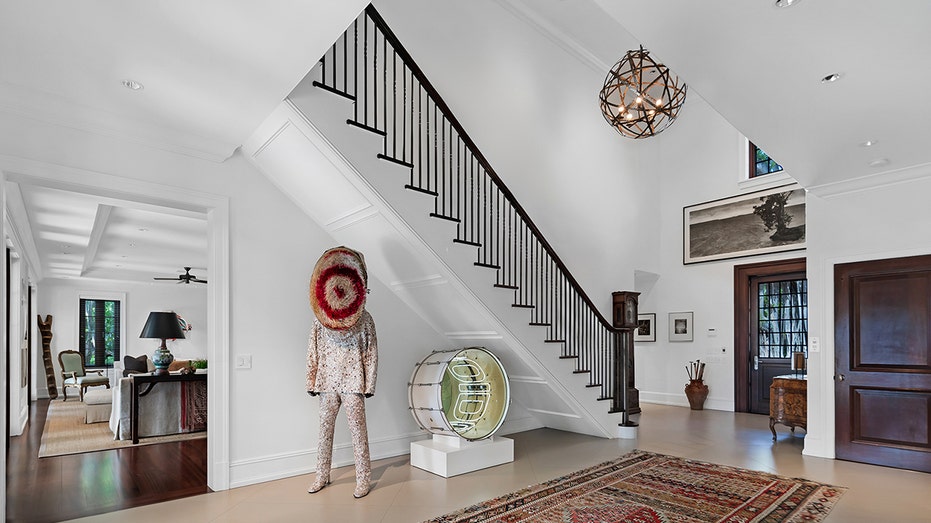 The entryway features a grand staircase leading to the upper levels and a double height foyer.