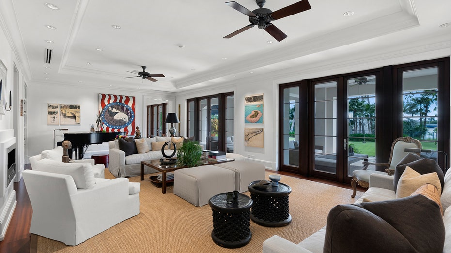 The living room includes multiple white couches and French doors leading to the backyard.