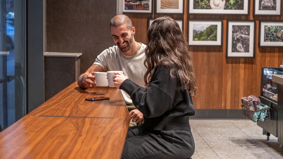 The inside of a redesigned Starbucks with two people at a high top drinking coffee.