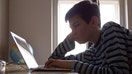 A boy sits in shadow at a laptop computer on Oct. 27, 2013. - Fox Business News