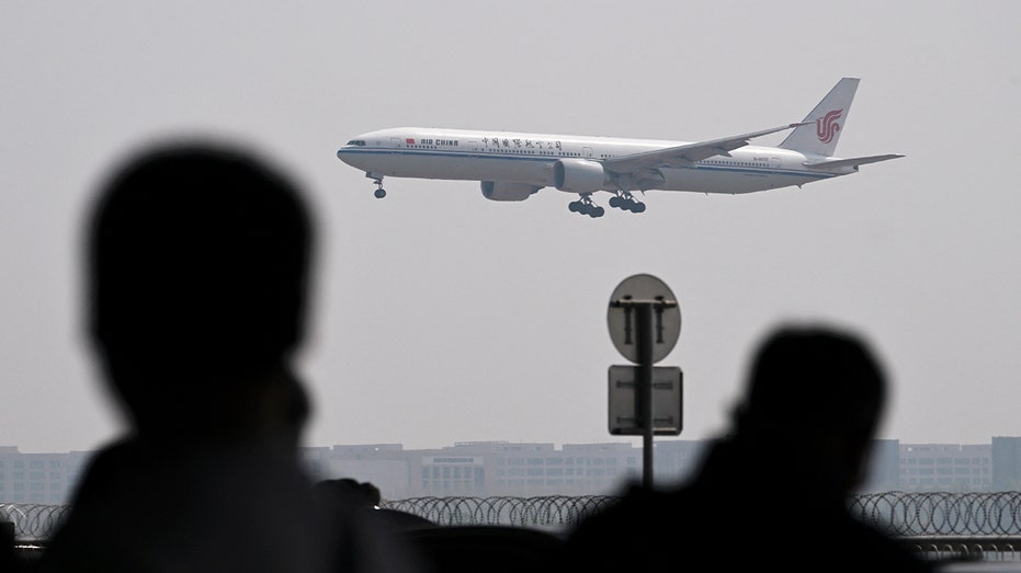 The plane flies while people watch