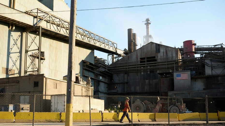 A worker walks around a steel mill facility.