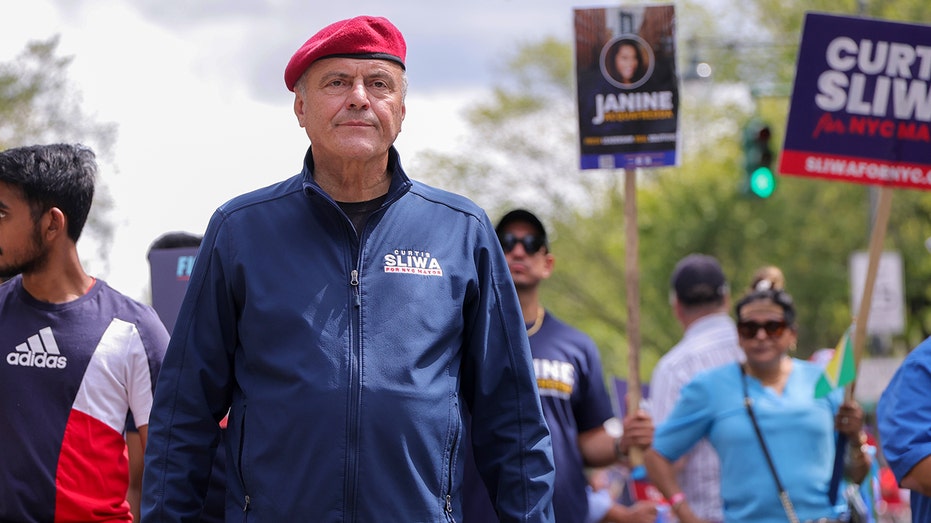 Curtis Sliwa walks on street with supporters
