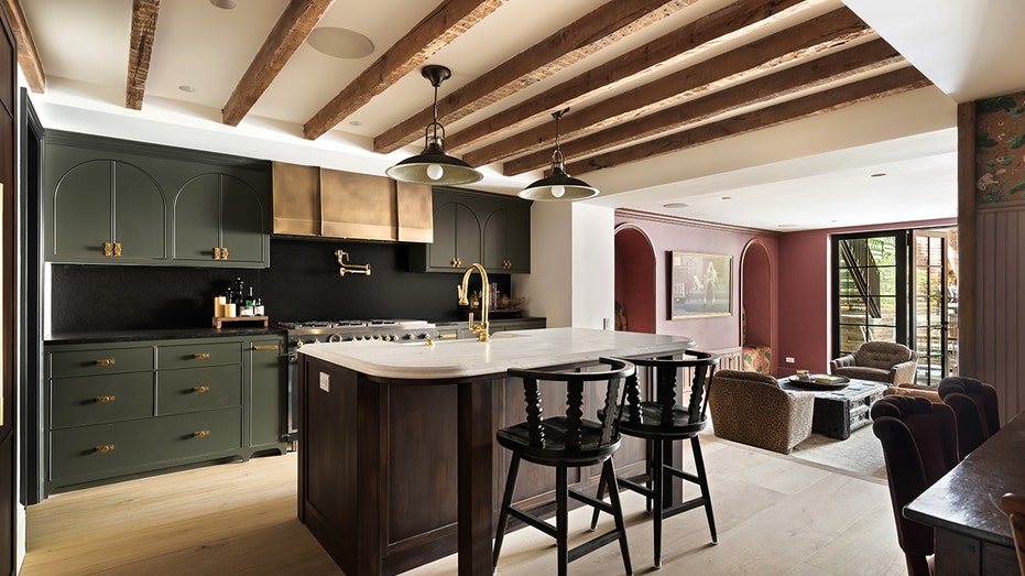 The kitchen features exposed wood beams on the ceiling, an eat-in center island and green cabinets.
