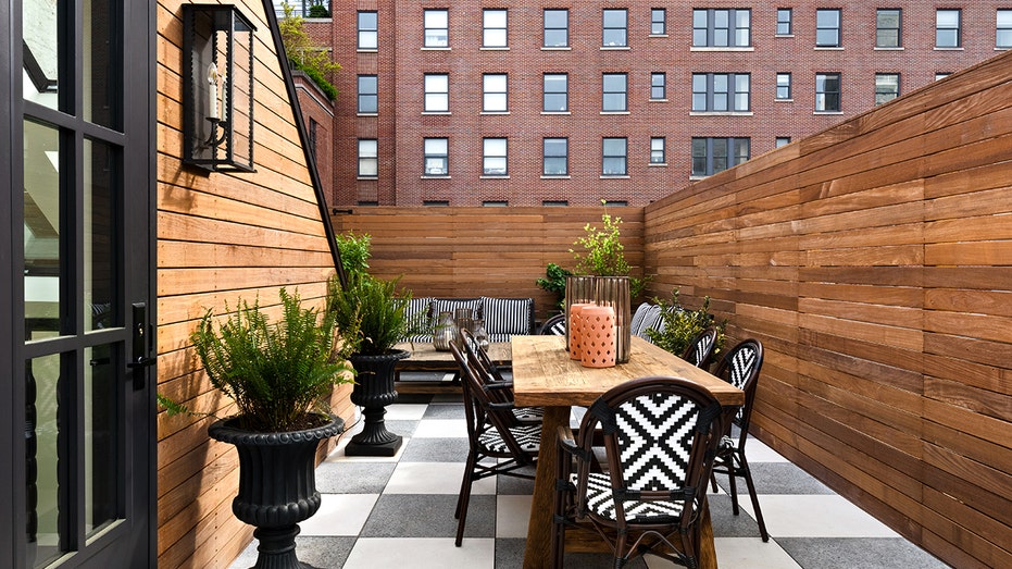 The master bedroom opens onto a private outdoor terrace with black and white rugs and chairs.